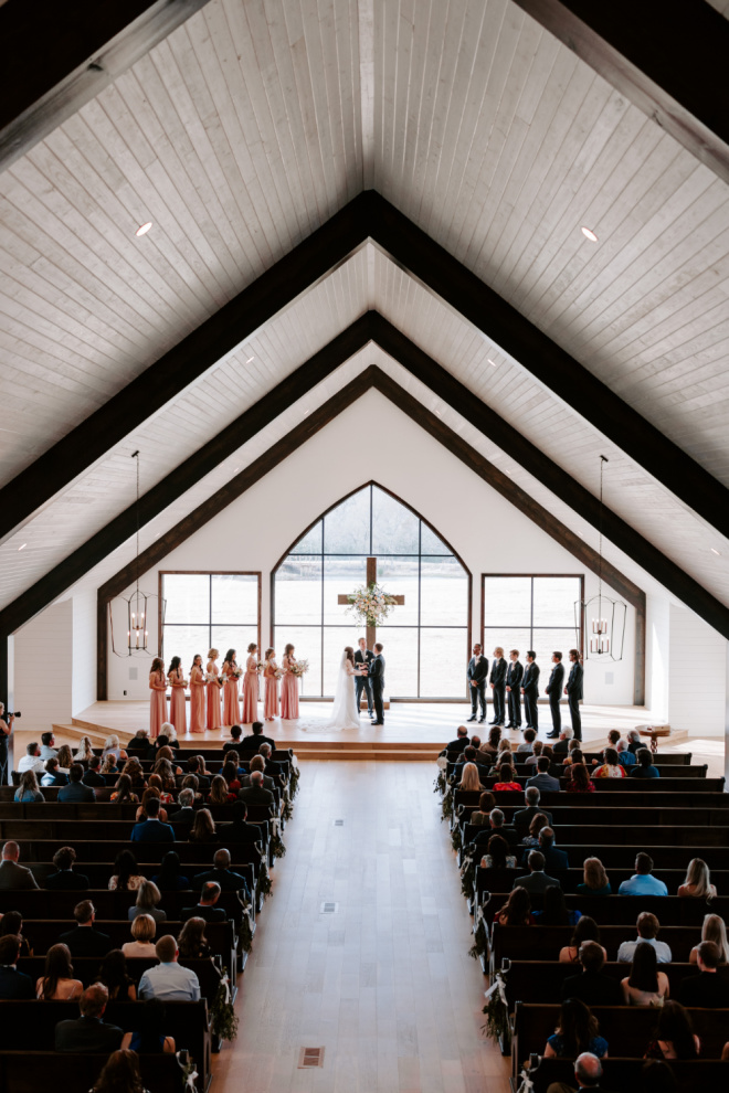 The bride and groom hold hands at the alter as they exchange vows in front of their friends and family.