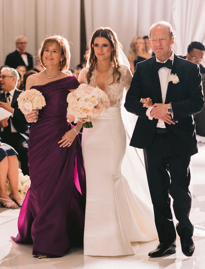 The bride's parents walking the bride down the aisle.