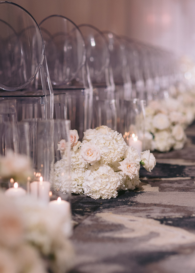 White and blush floral arrangements, lit candles and ghost chairs at a wedding ceremony at the post oak hotel. 