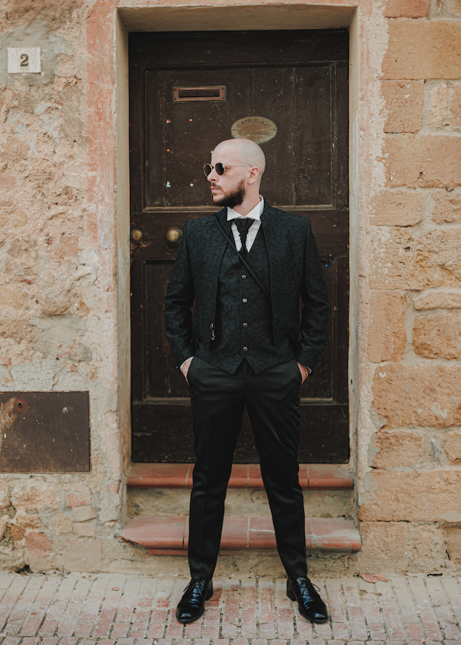 The groom looking to the side with his hands in his pockets before the wedding ceremony. 