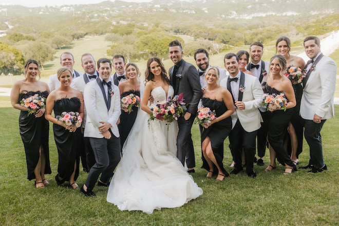 The bride and groom smiling with their wedding party.