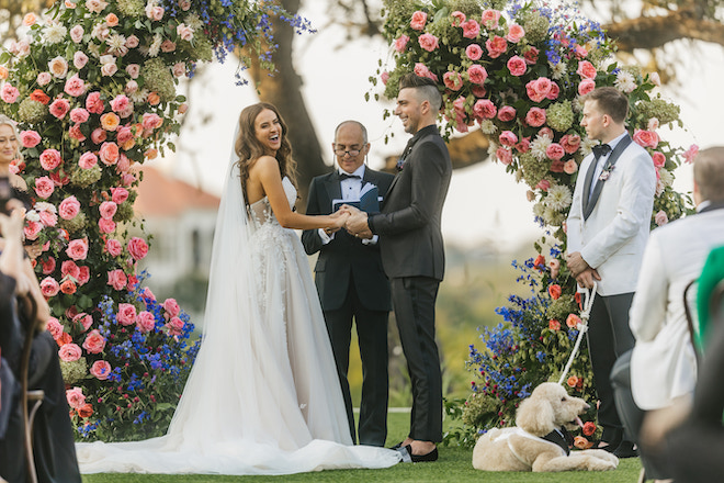 The bride and groom laughing as they hold hands during their wedding in the Austin hill country.