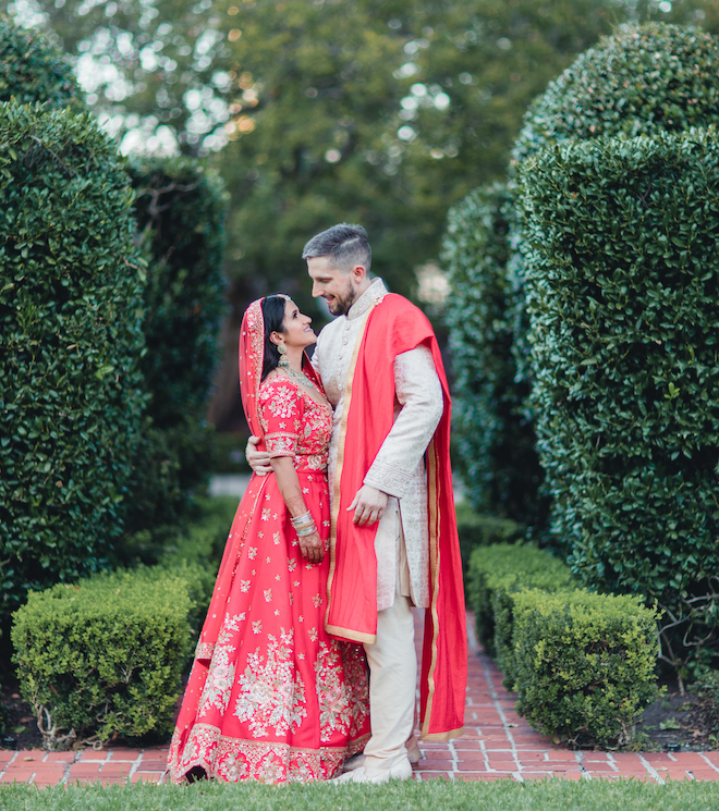 The bride and groom smiling at each other in a garden.