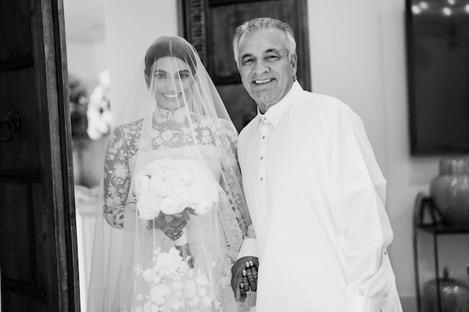 The bride and her father smiling before walking down the aisle at the beautiful backyard ceremony.