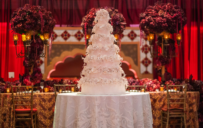 Grand white wedding cake covered in white florals.