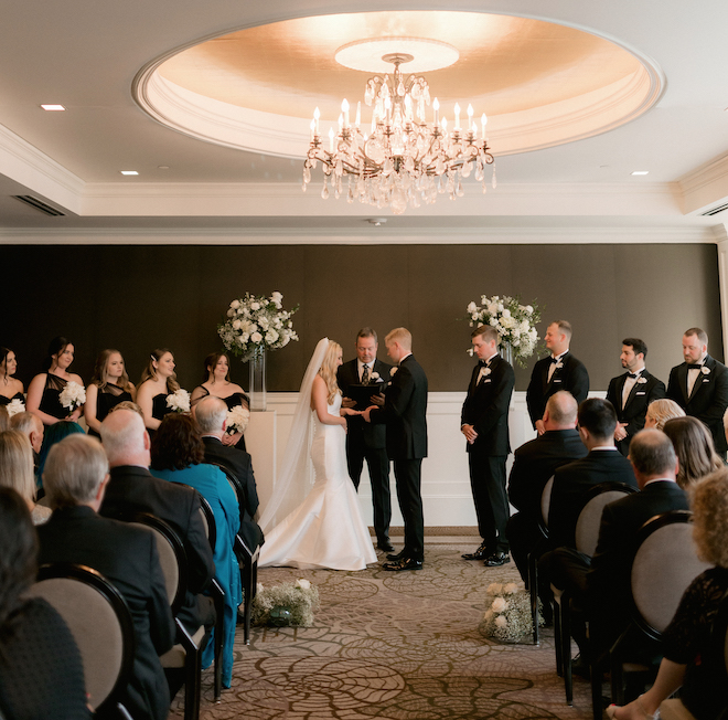 The bride and groom holding hands at the alter during their sophisticated ceremony.