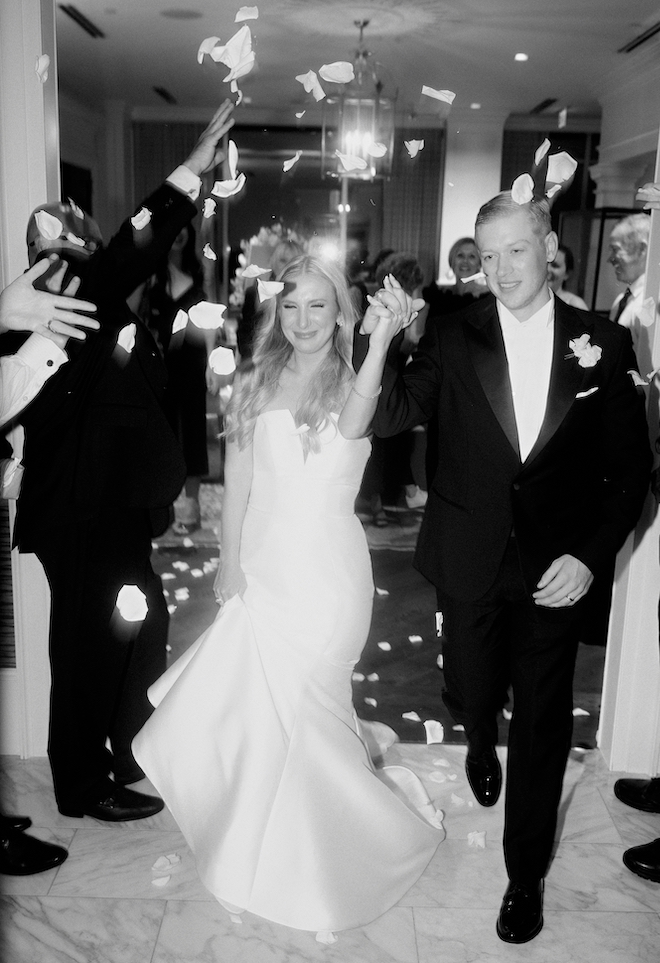 The couple hold hands during their rose petal send-off.