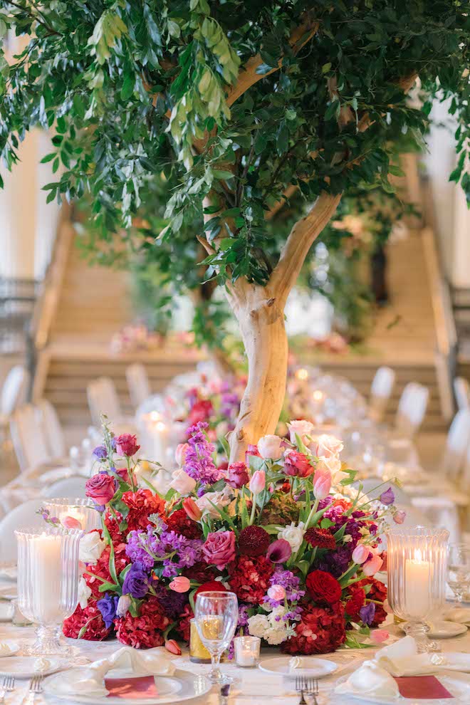 Pink, red and purple florals decorating the center of the reception tables at a luxurious Houston wedding.