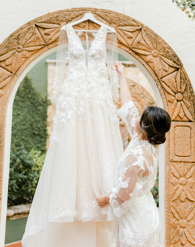 A bride reaches for her wedding dress hanging outside at the Bell Tower on 34th.