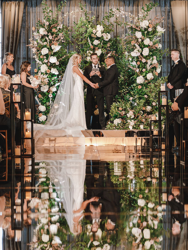 The bride and groom holding hands at their black, champagne and blush wedding ceremony.