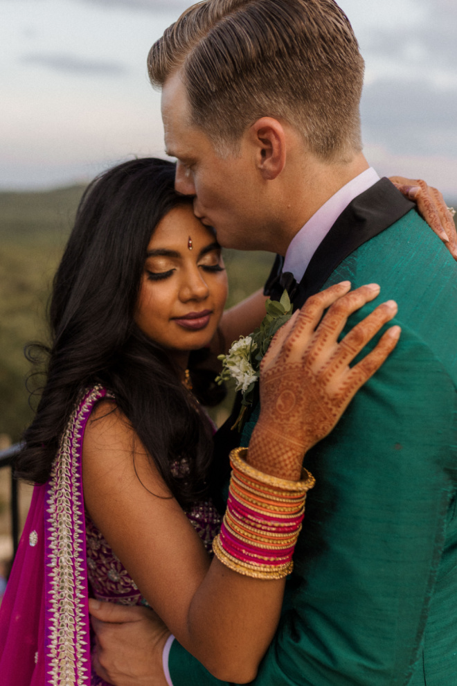 South asian bride with bridal henna embracing a groom at their al fresco wedding in Austin, Texas.