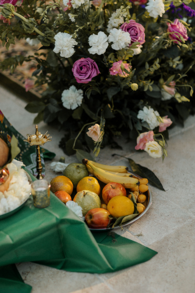 Traditional Indian wedding rituals are displayed next to a bouquet of white and mauve flowers. 