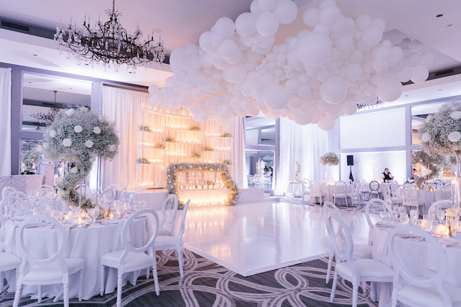 Ballroom wedding reception decorated with babies breath, lit candles and white balloons at Omni Houston Hotel.