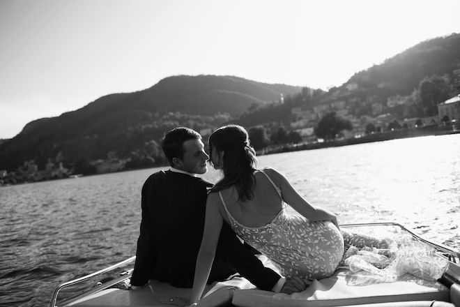 The bride and groom sitting on the back of the boat about to kiss.