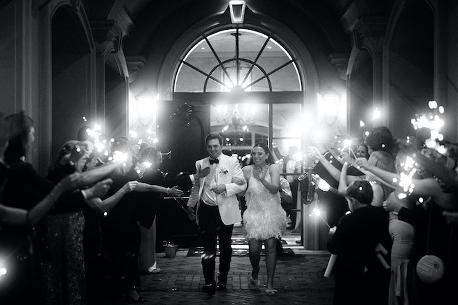 The bride and groom smiling and waving during their sparkler send-off. 