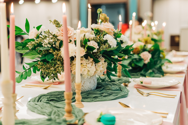 Pink and white pillar candles with floral arrangements decorating the reception dinner table.