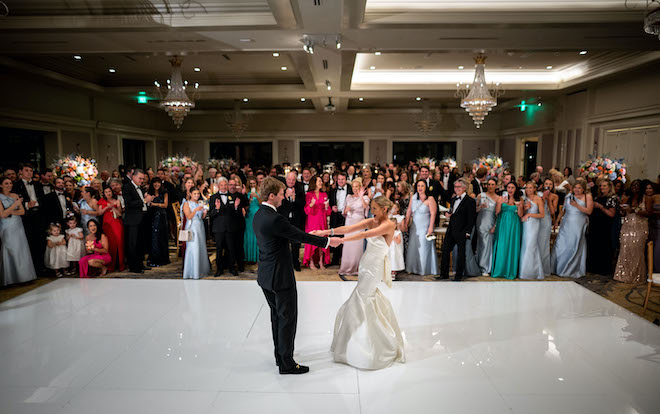 The bride and groom on the dance floor as the guests watch their first dance.