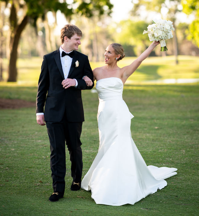 The bride holding her bouquet up in the air while walking with the groom.