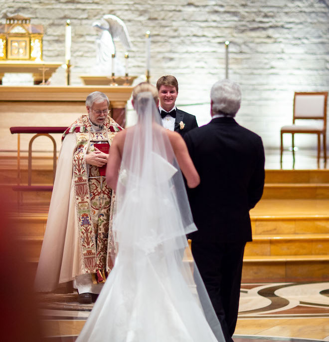 The bride and her father walking down the aisle to the groom.