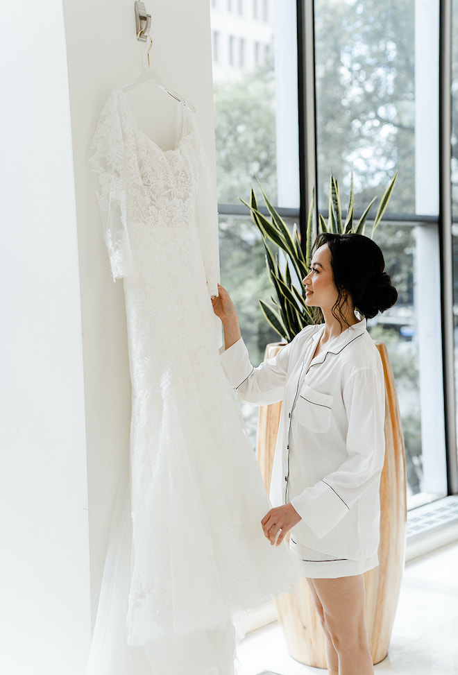 The bride holding her hanging wedding dress.