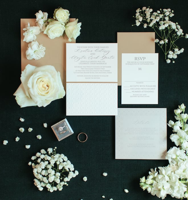 The oyster-toned invitation suite surrounded by roses and baby's breath.