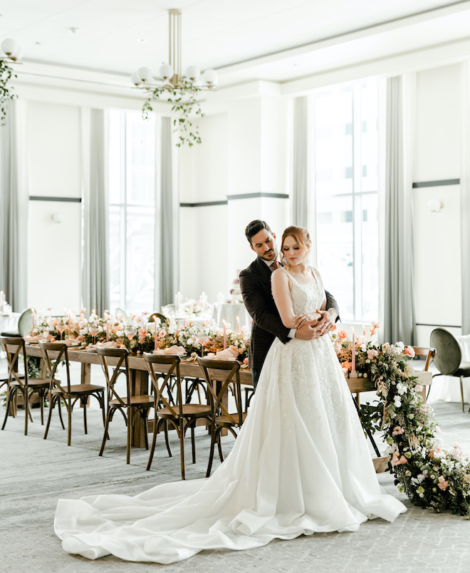 The bride and groom posing in front of the reception table at the light & airy wedding editorial in the Laura Hotel ballroom.