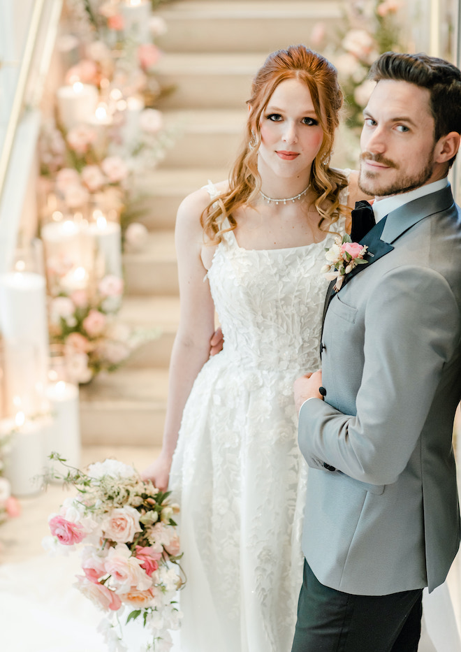 The bride and groom smiling on the grand staircase.