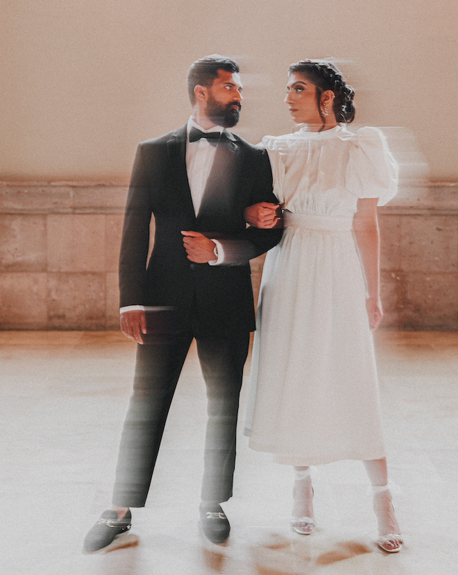 The bride and groom linking arms and looking at eachother.