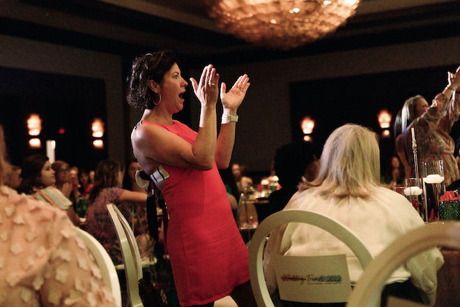 A woman standing up and clapping.