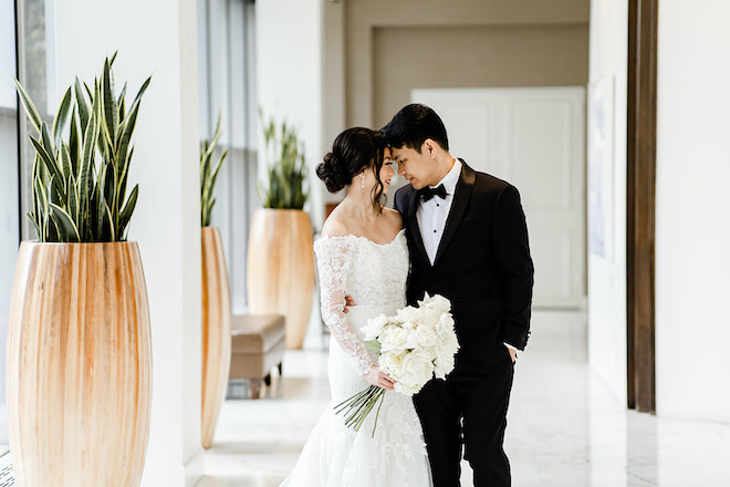 A bride and groom smiling at each other in the hallways of The Whitehall Houston.