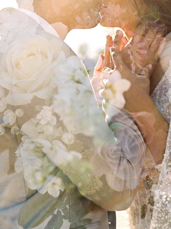 The bride and groom kissing with floral reflections on the photos.