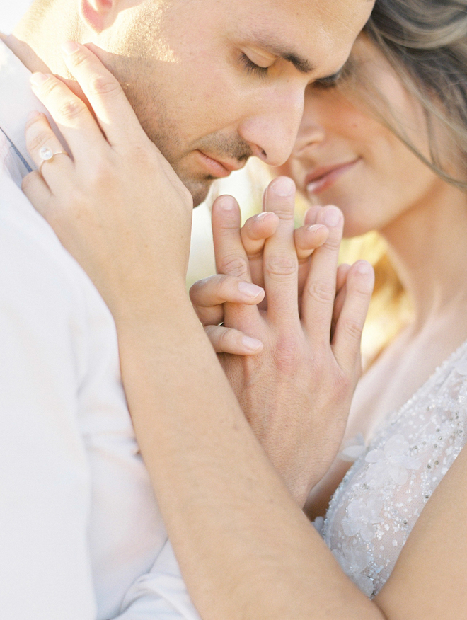 The bride and groom touching foreheads and locking hands.