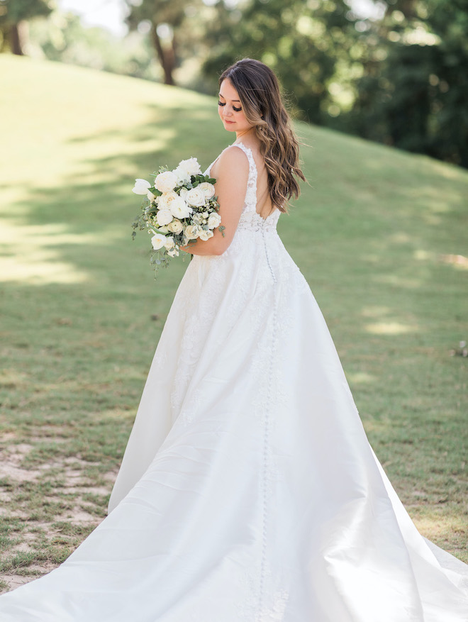 The bride looking down with her bouquet outside before their white sage and blush wedding. 