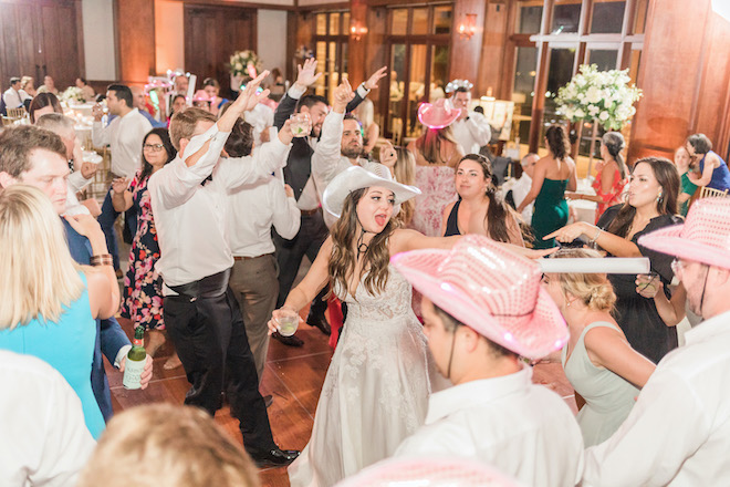 The bride and guests wearing sparkly cowboy hats dancing at the reception. 