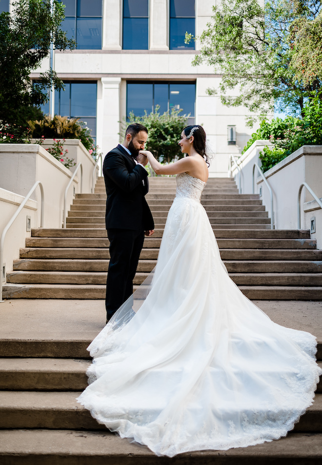 The groom kissing the brides hand on a staircase. 