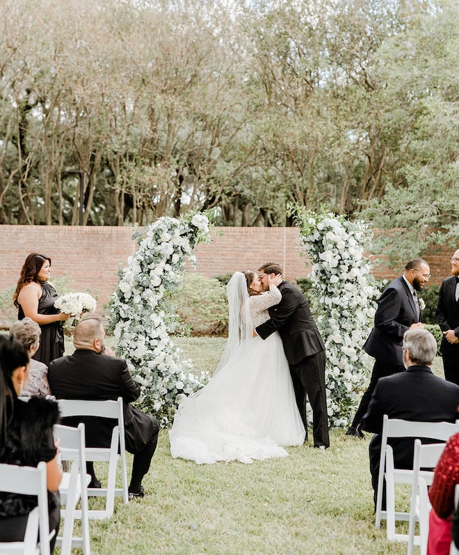 The bride and groom kissing in front of the altar. 