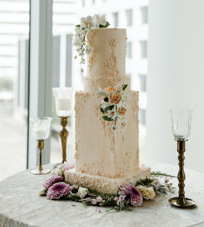 Wedding cake replica of the Houston skyscraper with fondant florals decorating the three tiers by Not Your Ordinary Cakes in Houston, TX.