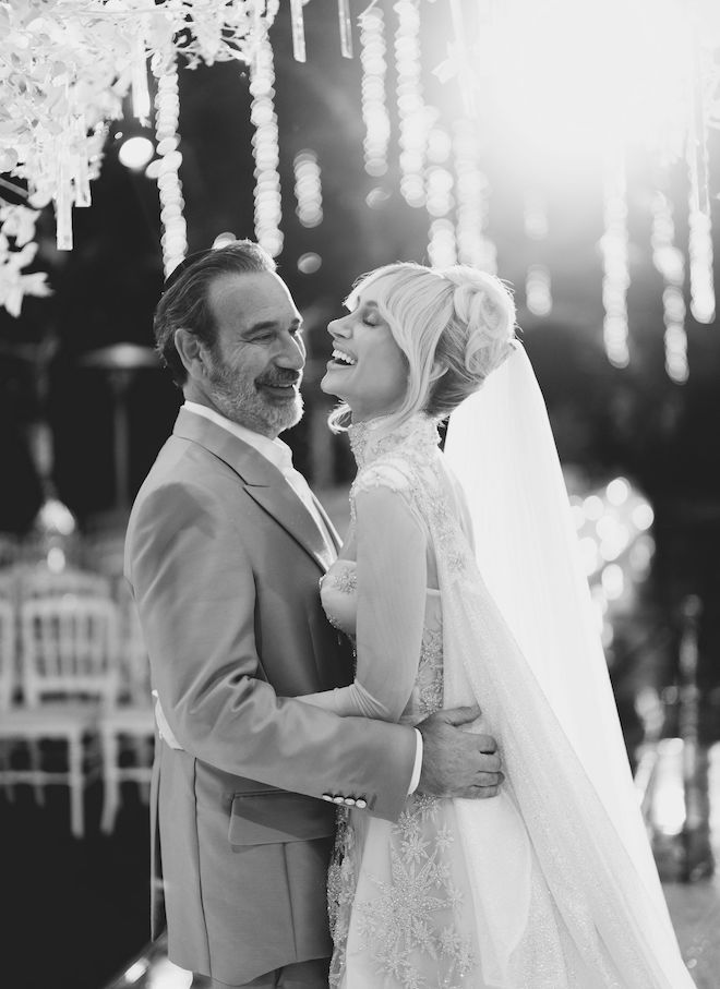 The bride and groom hugging as the bride laughs and the groom smiles at her. 