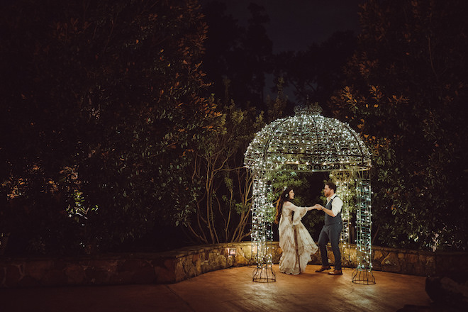 The bride and groom dancing under a lit gazebo. 