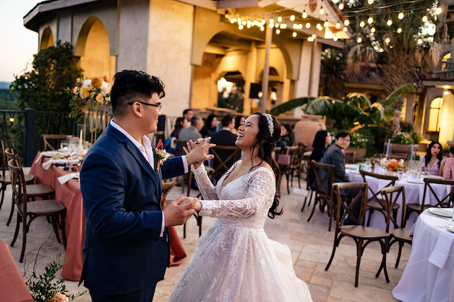 The bride and groom laughing while dancing during their alfresco reception. 