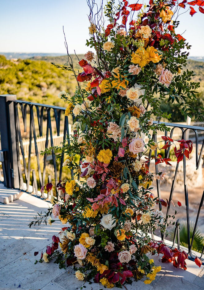 A floral arrangement with autumn flowers in shades of red, yellow, peach and sand. 