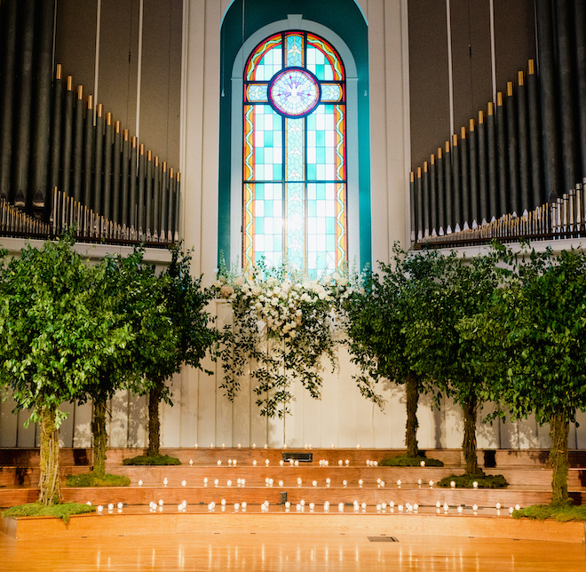 The altar at the church decorated with greenery, gardenias and candlelight. 