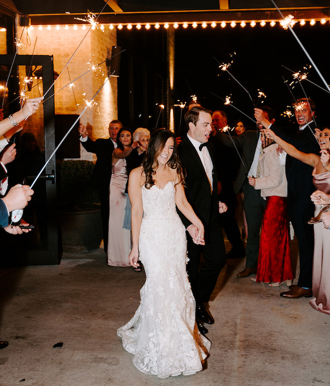 The bride and groom holding hands walking through their sparkler send off. 