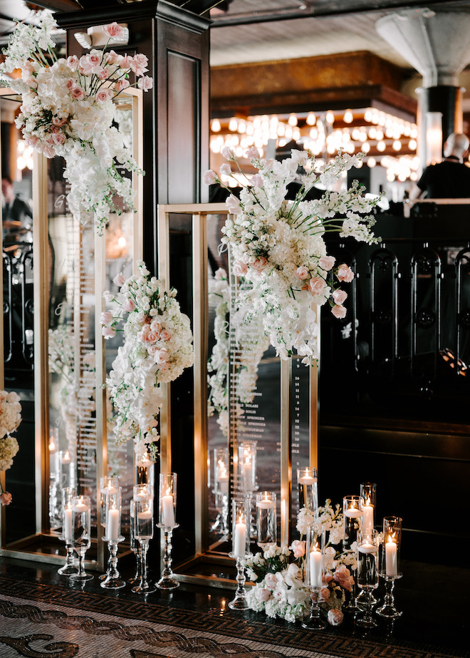 A gold framed seating chart with white and blush florals decorating it. 