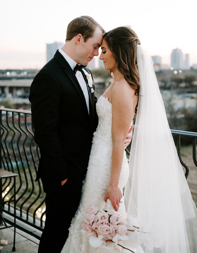 The bride and groom smiling and touching foreheads on the balcony of The Astorian. 