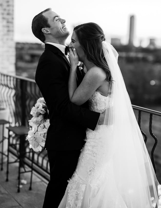 The bride and groom laughing on a balcony at The Astorian. 