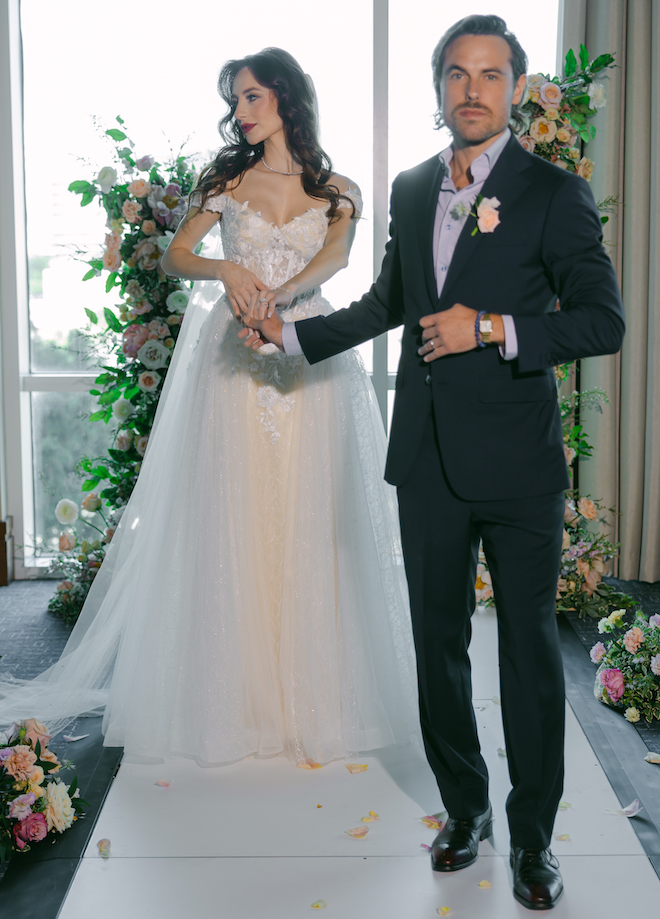 The groom holding the bride's hand leading her down the aisle. 