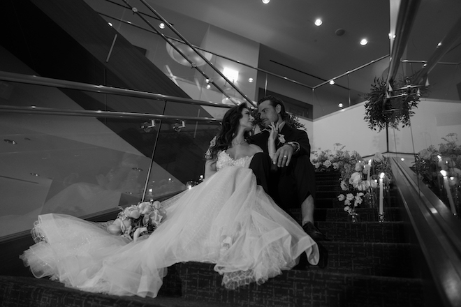 The bride and groom looking at each other while sitting on the stairs at The Westin Houston Memorial City.