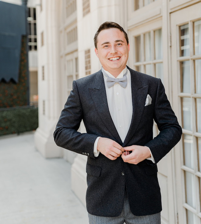 The groom smiling buttoning up his suit jacket.