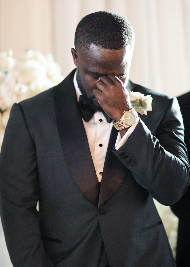 The groom wiping tears away at the altar. 